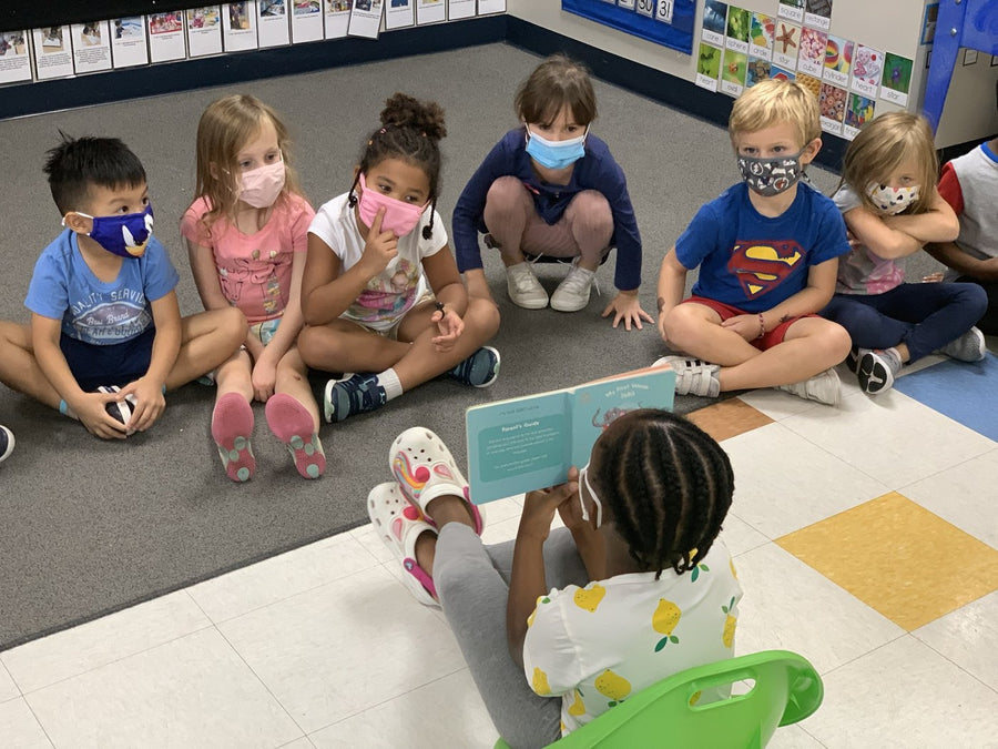 A child reading a KOLI & OLUM book to her class